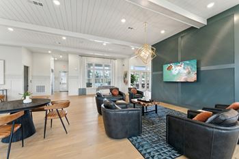A modern living room with a black couch and a painting on the wall.